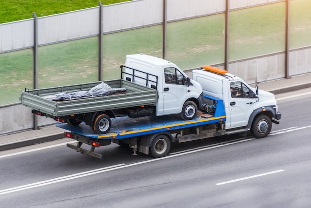 a truck is transporting another small truck on the road