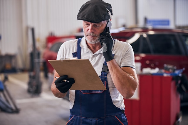 beaded male worker checking notes while having phone conversation