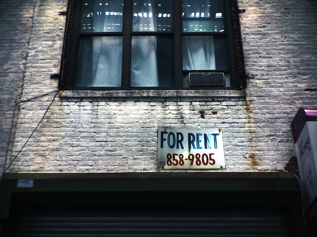 for rent sign on wall below window glass of building