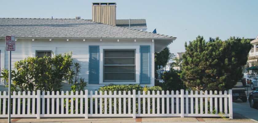white and blue house beside fence